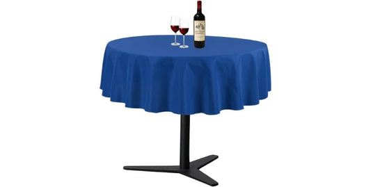 Royal blue round tablecloth on modern black round table with bottle and two glasses of red wine