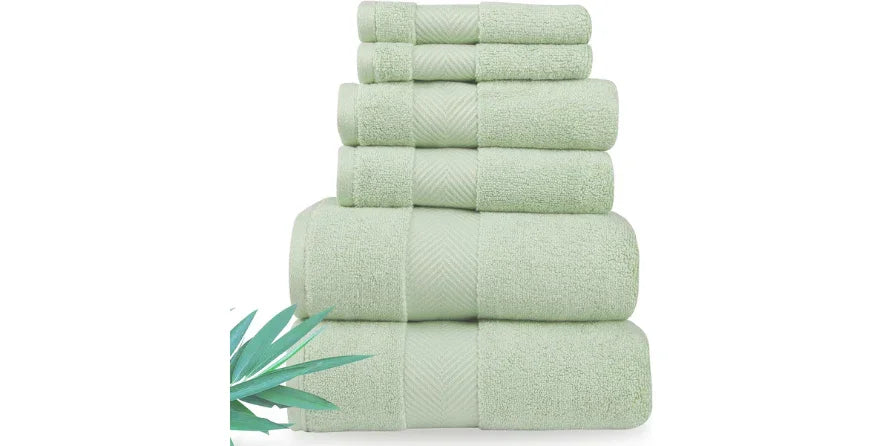 Stack of soft light green plush bamboo viscose bath towels with green leaf on white background